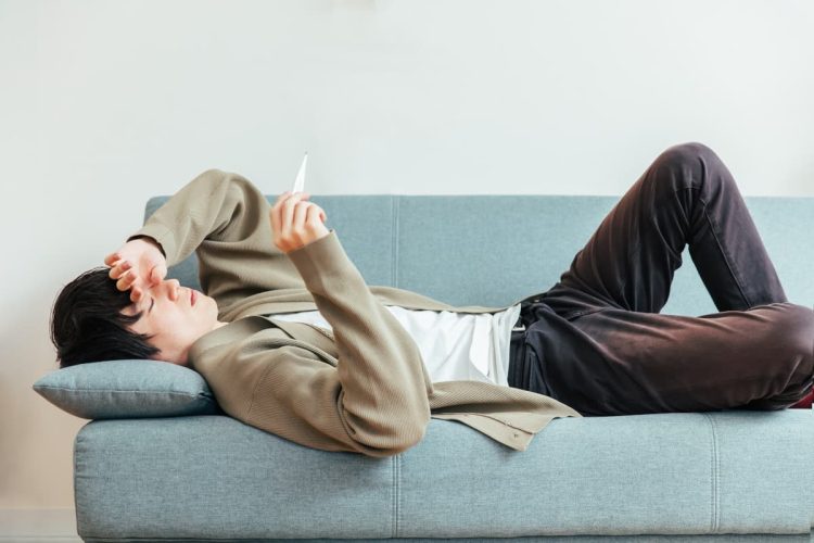 体調不良でソファーで横になる男性