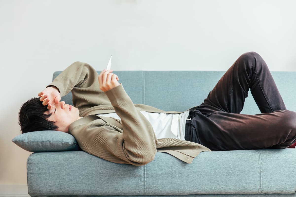 体調不良でソファーで横になる男性