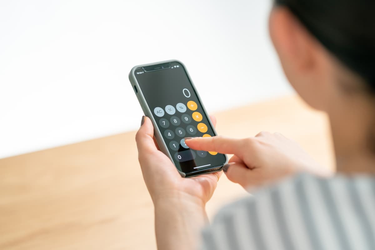 スマホの電卓で計算をする女性