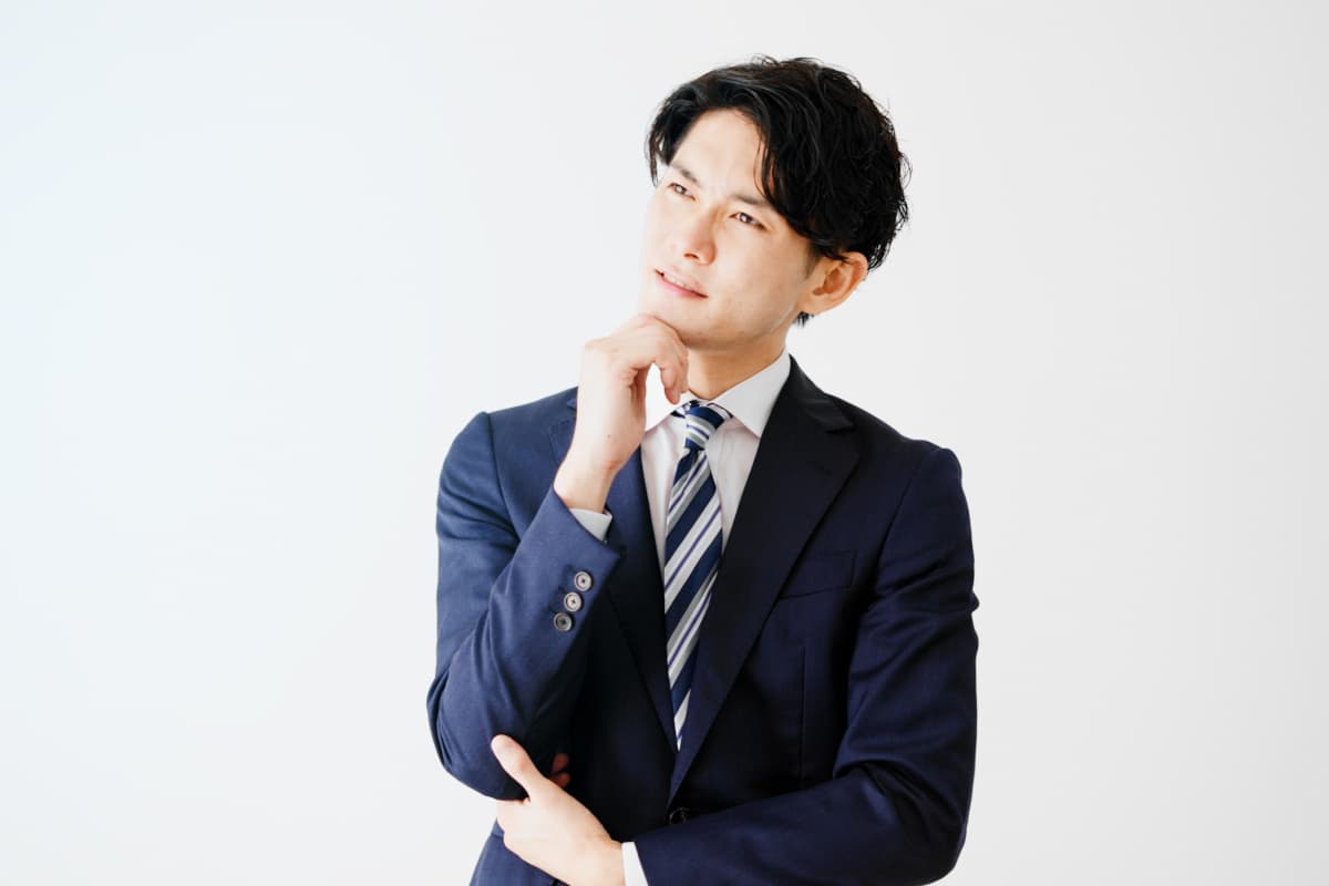考え事をするスーツ姿の男性