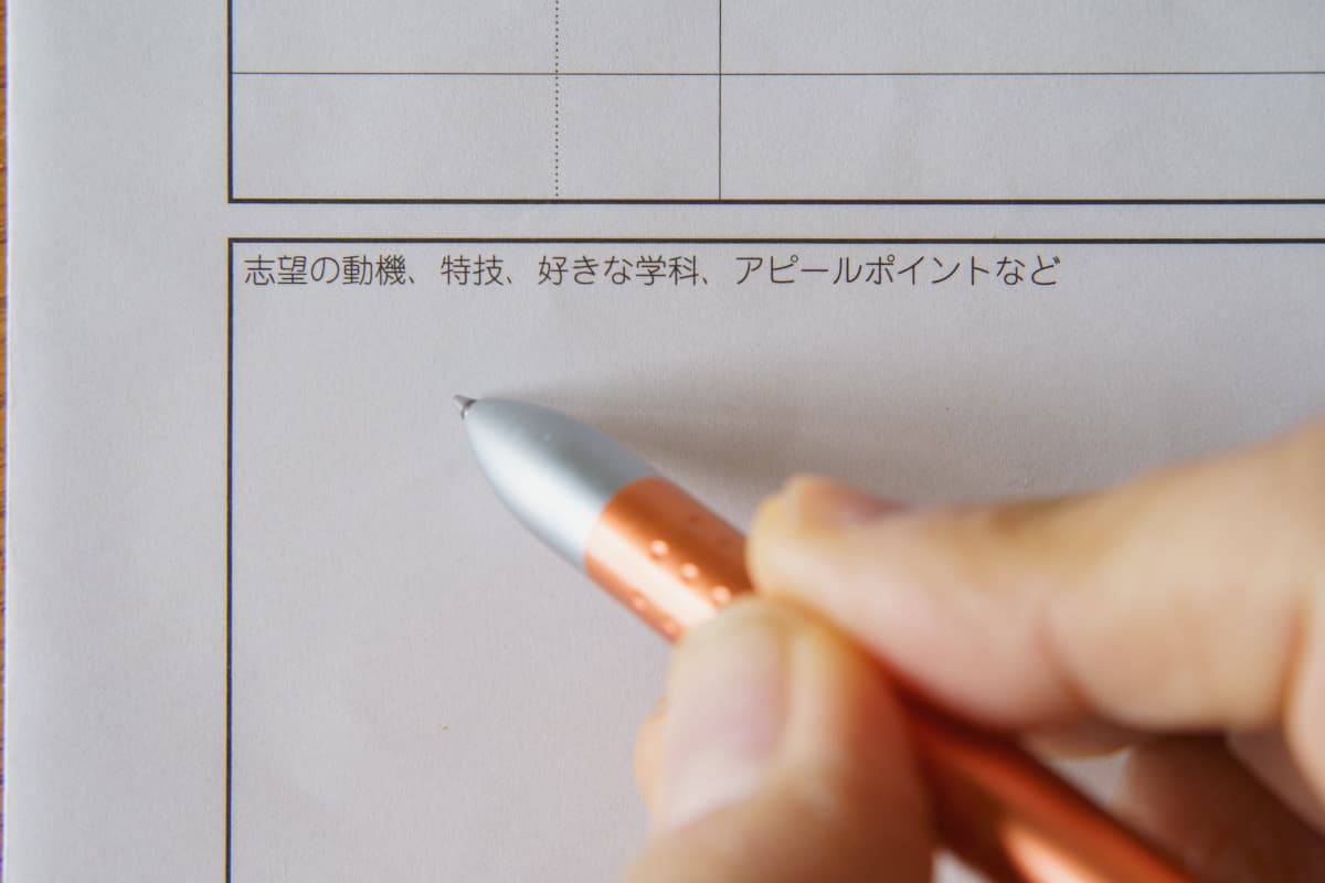 ボールペンで志望動機を書く女性の手