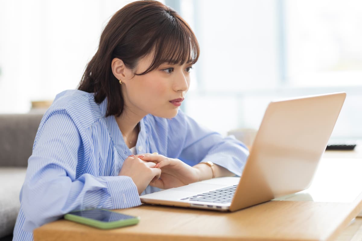 パソコン画面を見ながら考え事をする女性