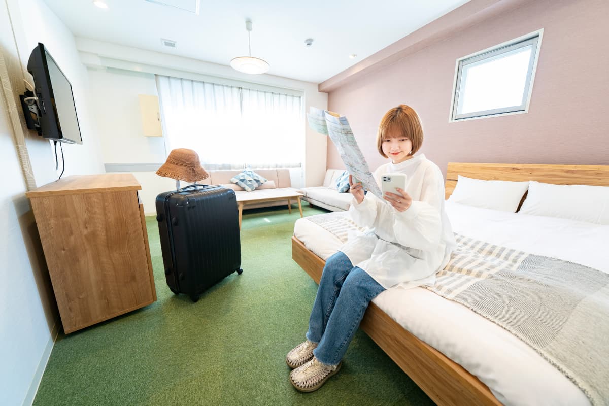 ホテルの客室でスマホを触る女性