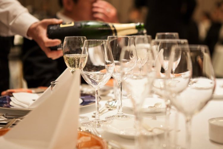 テーブルの上に置かれたワイングラスにワインを注ぐ