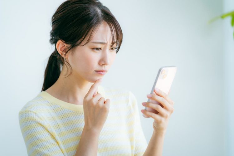 スマホを見て悩む女性