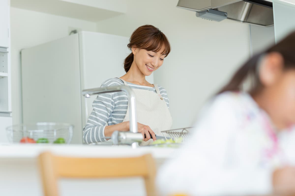 子どもを見守りながら調理をする主婦