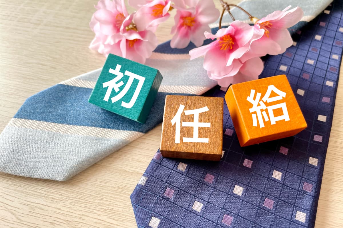 ネクタイの上に置かれたカラフルな初任給と書いたブロック