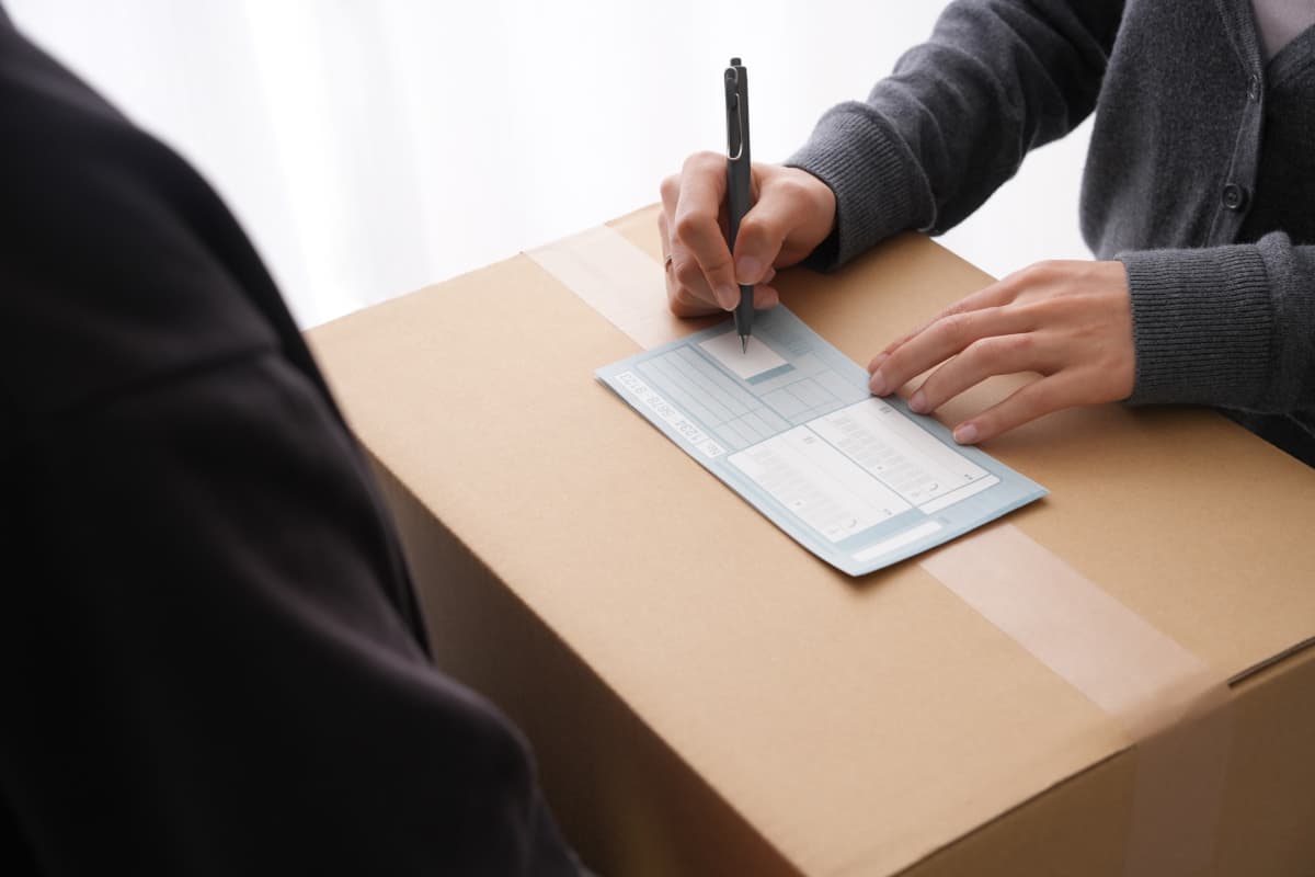 荷物を送るために送り状を書いている人
