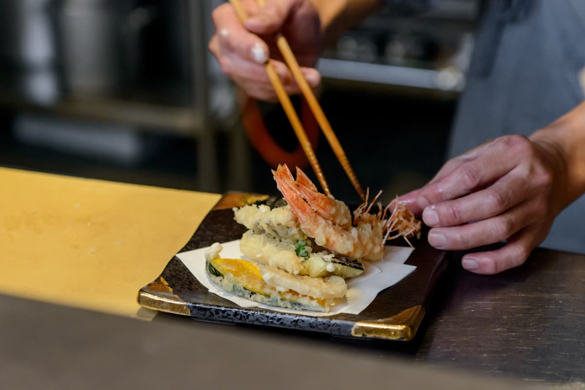 お皿に天ぷらを盛り付ける板前