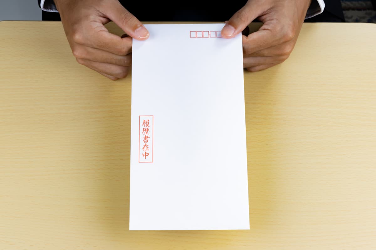履歴書の入った封筒を渡す人