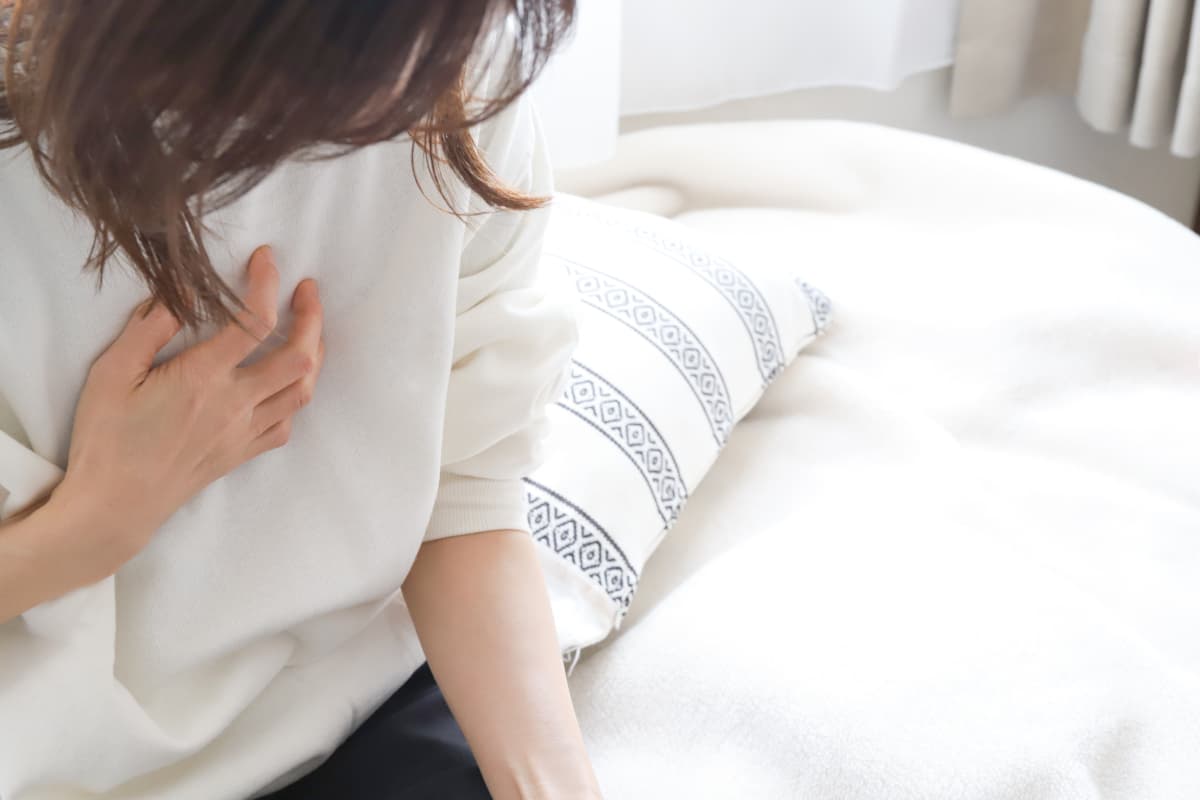 ベッドに座る体調不良の女性