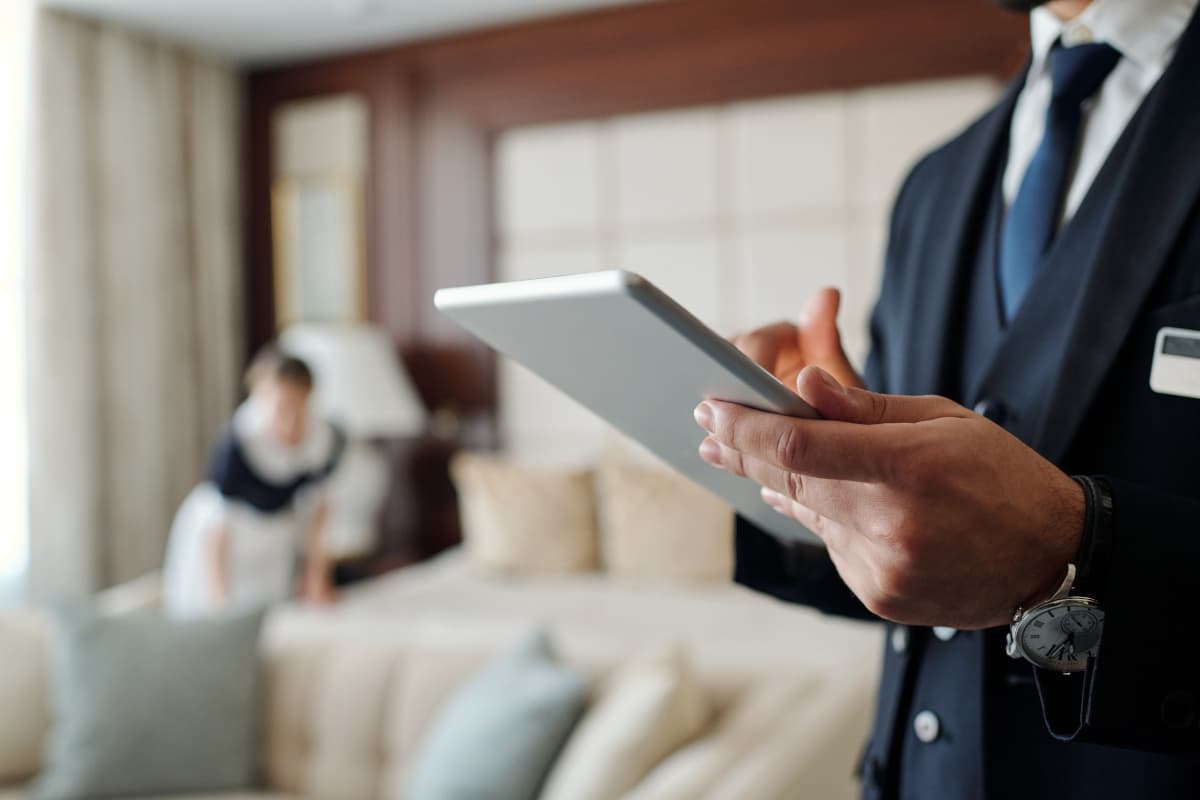 ホテルのハウスキーピングとタブレットを操作する男性の手