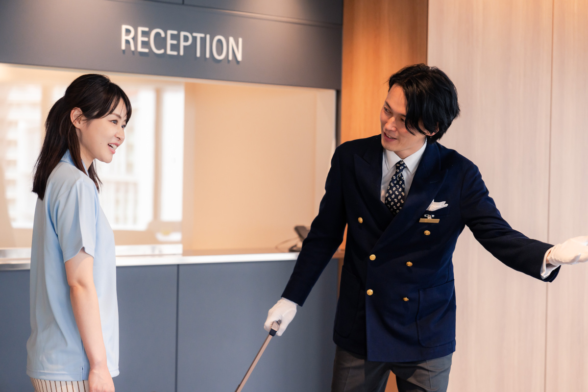 ホテルフロントでお客様の女性を案内するホテルスタッフ