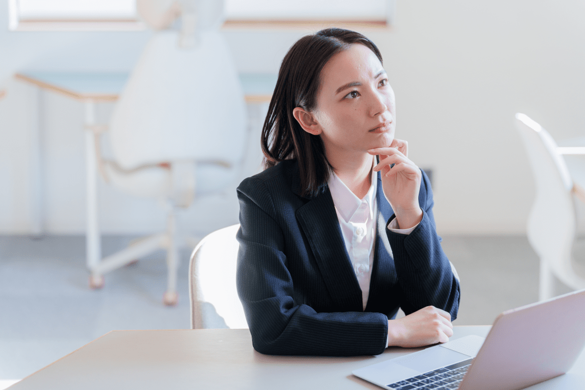 パソコンを前に悩むスーツを着た若い女性