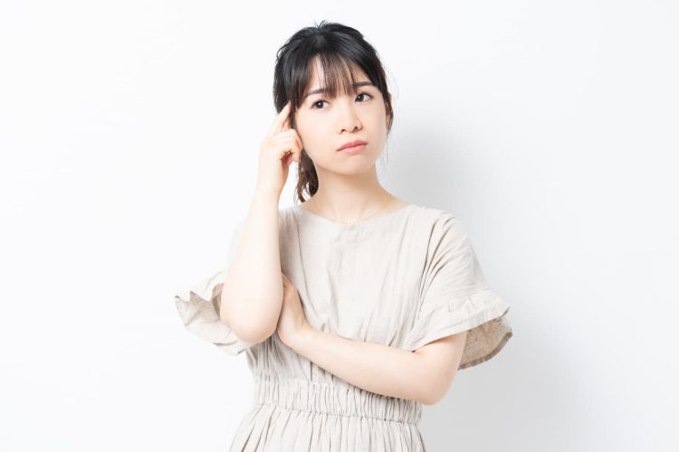 頭に手を当てて考えている女性