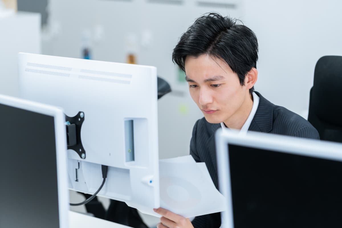 書類を見て考え事をするビジネスマン