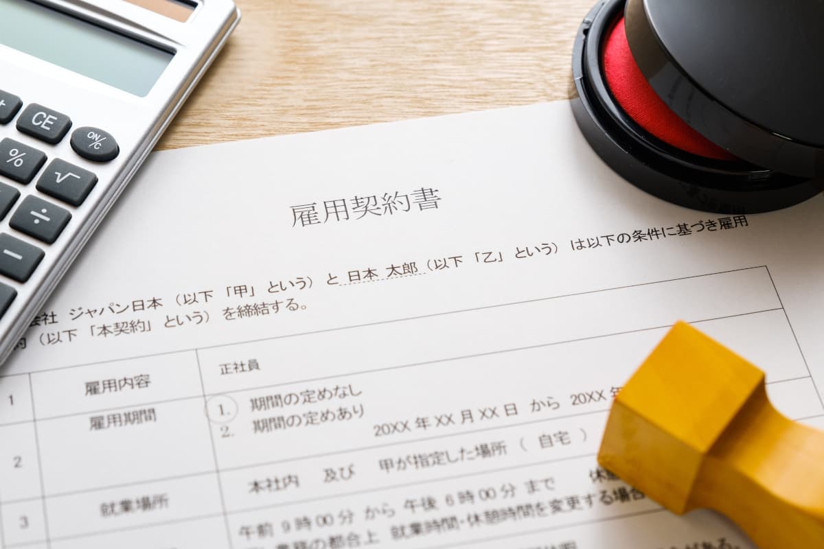 デスクの上に置かれた雇用契約書や電卓、印鑑