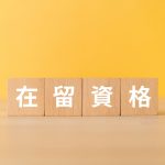 黄色い壁を背景にした在留資格と書かれた木のブロック