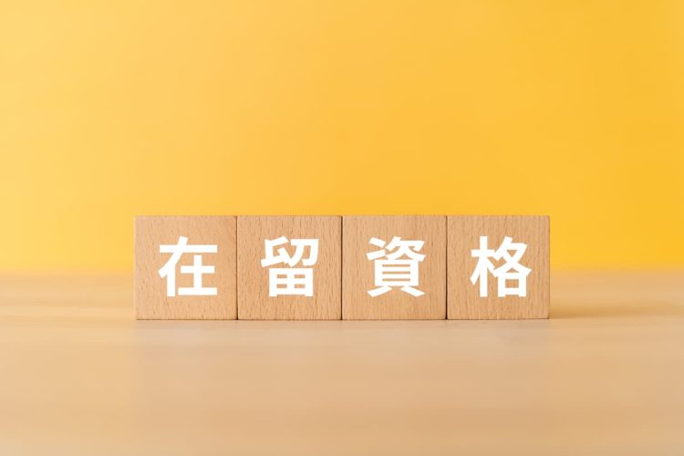 黄色い壁を背景にした在留資格と書かれた木のブロック