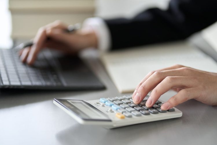 パソコンを見ながら電卓で計算する人の手