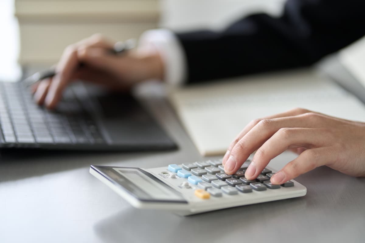 パソコンを見ながら電卓で計算する人の手