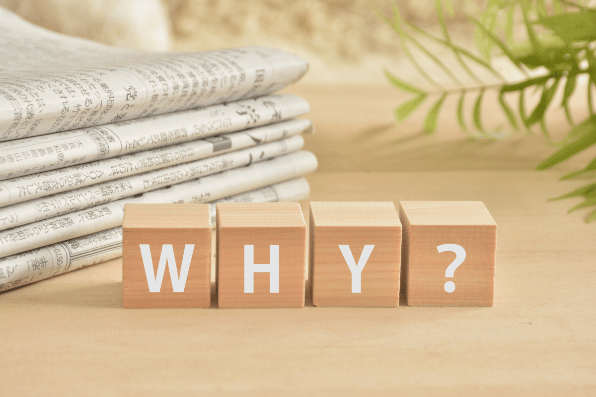 WHY？と書かれた積み木と新聞と植物