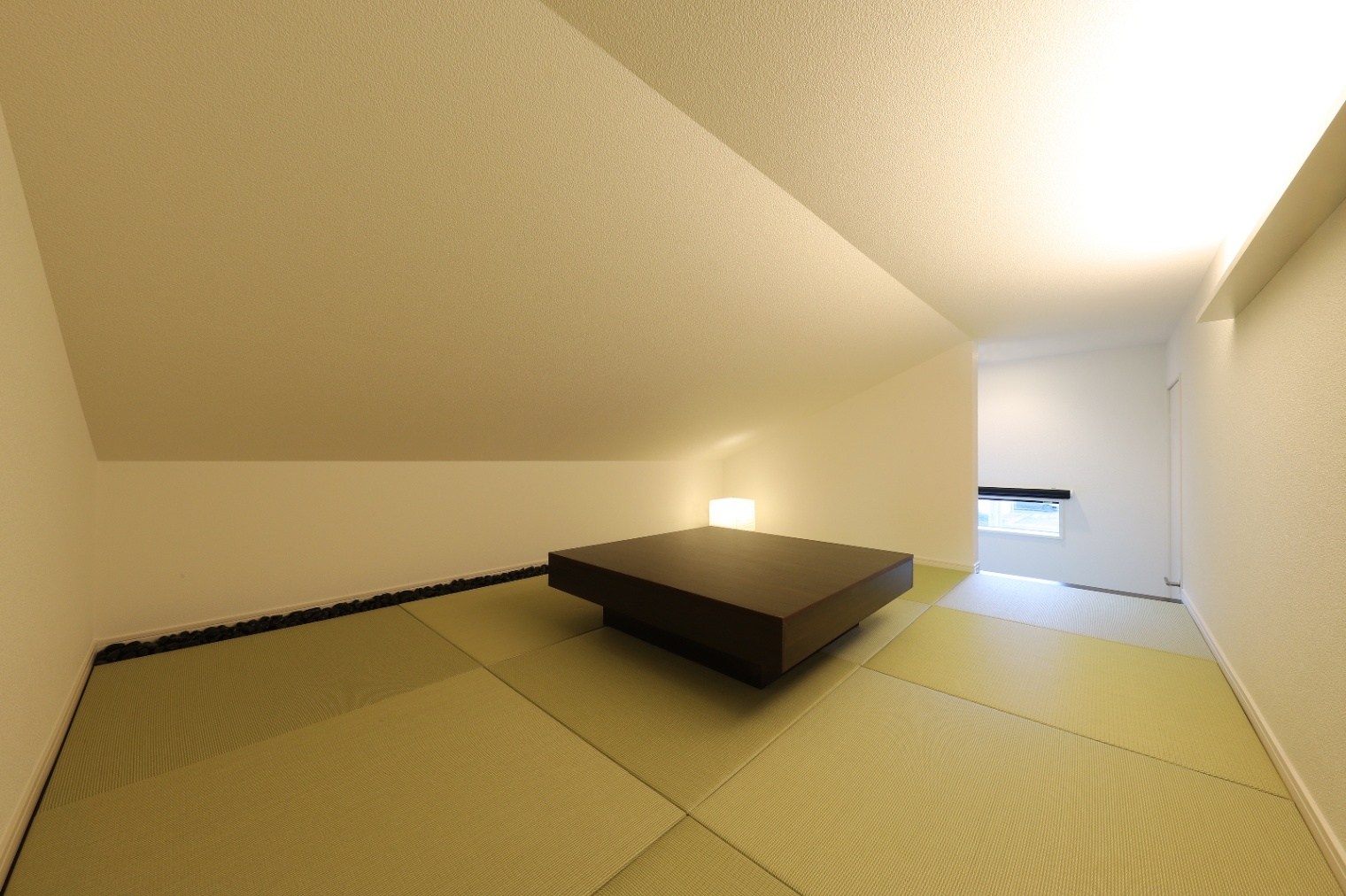 アイダ設計　｜コンパクトながらも心地良い畳の小上がりスペース。シンプルな家具配置で落ち着いた雰囲気を醸し出している。