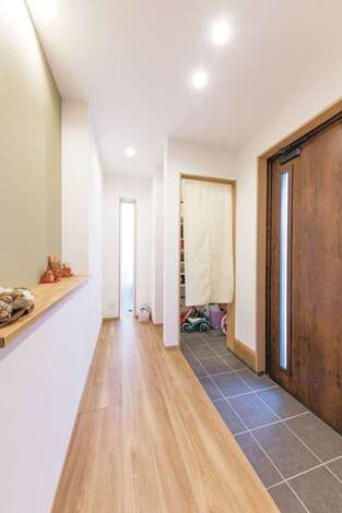 家族みんなでお出かけ準備ができるワイドスパンの玄関。奥行きのあるシューズクローゼットはご主人のサーフボードもすっぽり収納。正面の飾りニッチは、グリーンのアクセントクロスで爽やかに演出