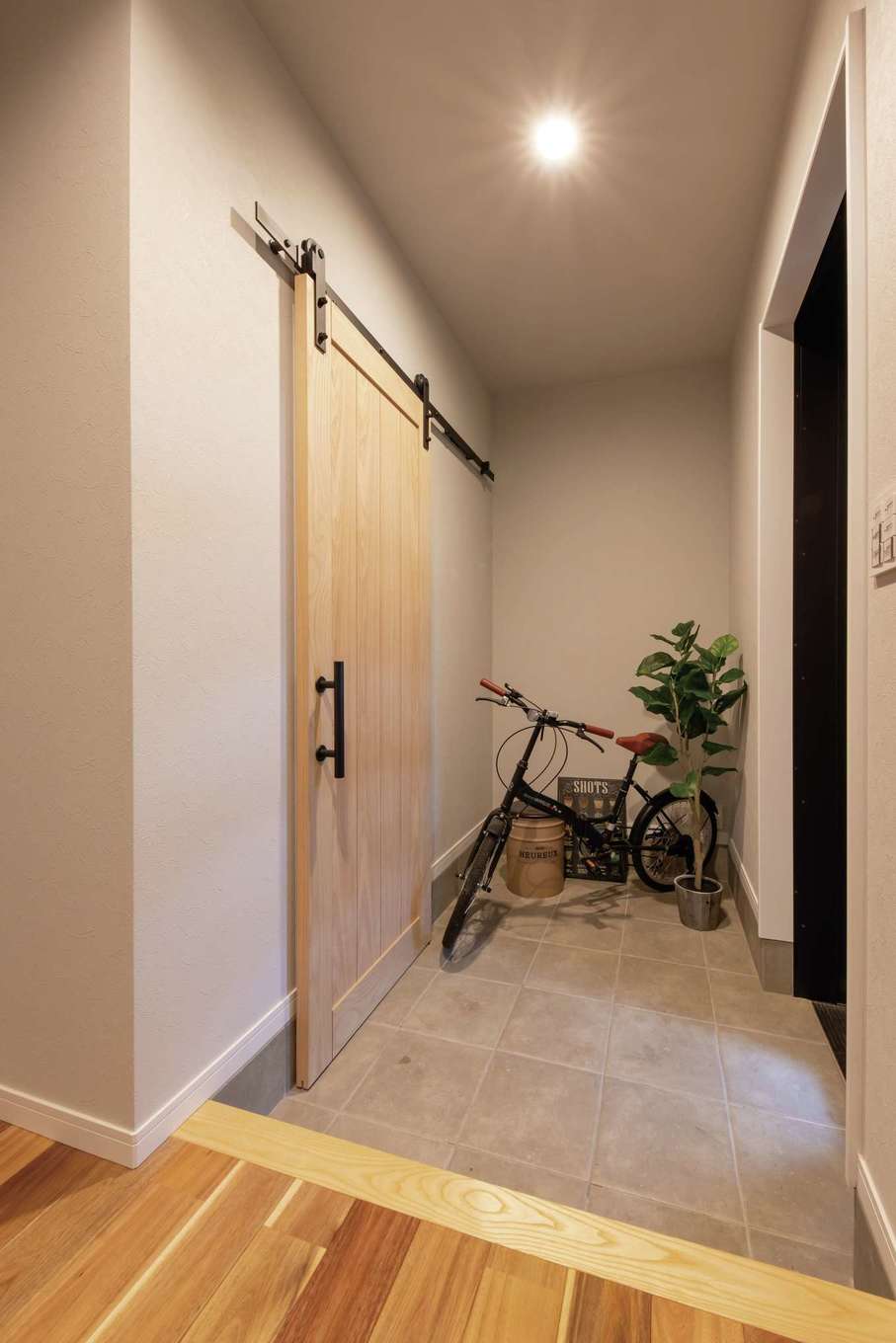Yamaguchi Design 【自然素材、平屋、ガレージ】土間やクロスをグレーで統一した玄関。シューズクロークにつながる造作のドアはいずれDIYで色を塗る計画