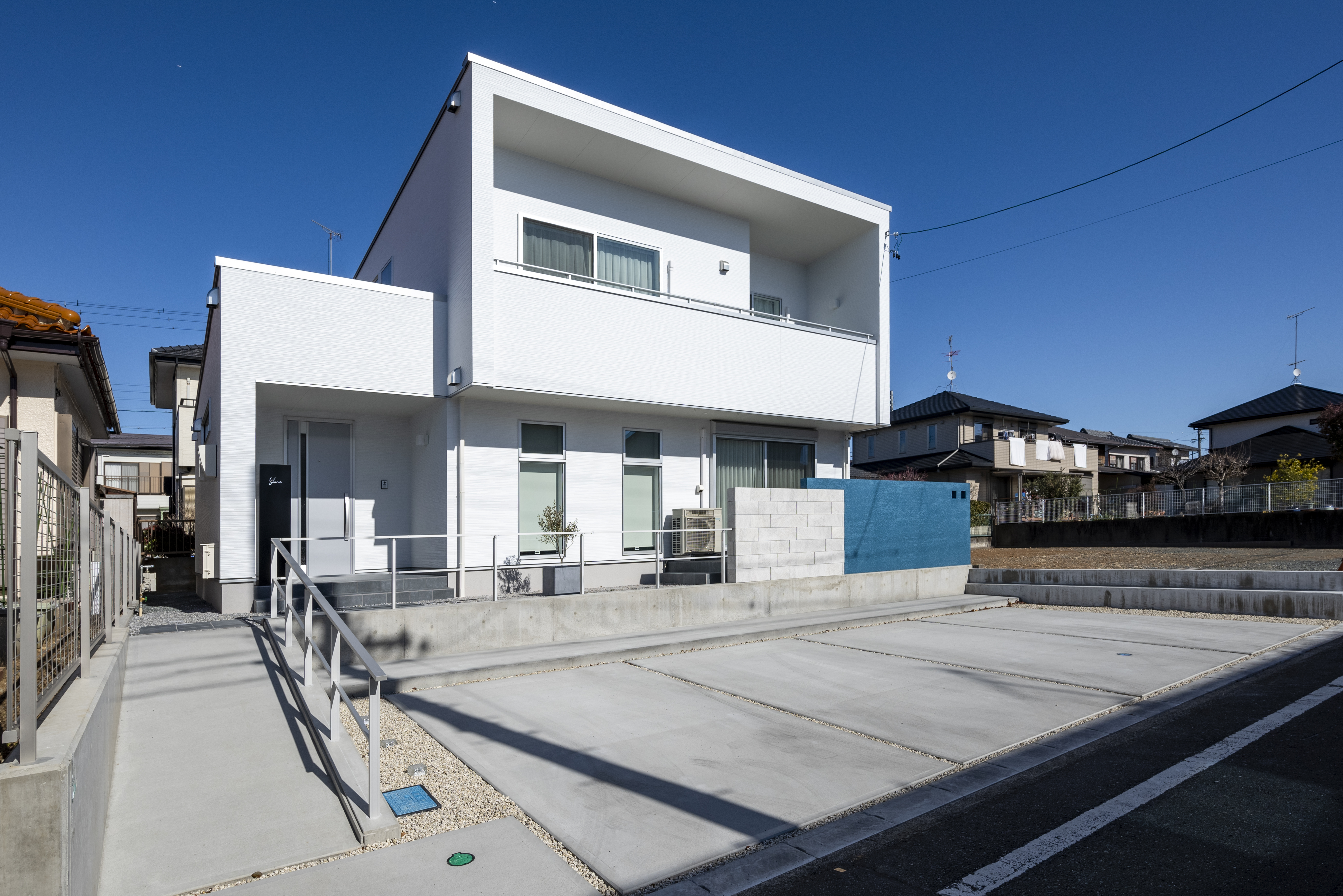 トキワハウス デザイン アンド ビルド（常盤工業）｜モダンな外観の住宅。白い壁が特徴で、雨や風から守る設計が施されている。広い前面スペースも魅力的。