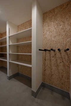 広々としたシューズクローク。棚とコート掛けが備え付けられており、靴や衣類の収納に便利である。カジュアルな雰囲気の壁紙が魅力。