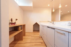 明るい照明が特徴のモダンなキッチン。広々としたワークスペースと収納が豊かで、快適な料理時間を演出する。