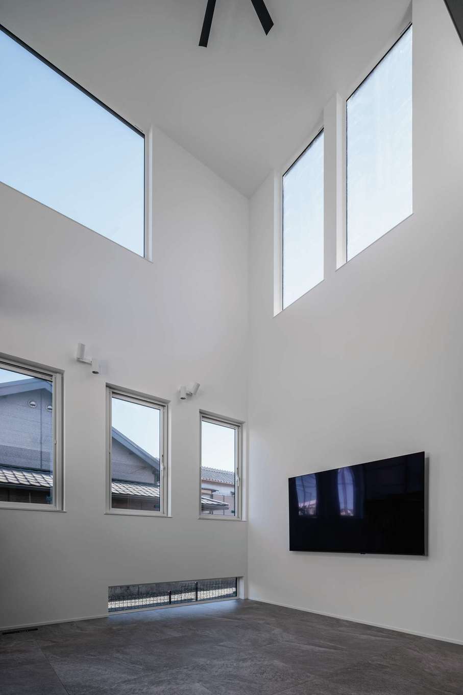 tact design firm【デザイン住宅、省エネ、間取り】南側に家があり、西側にも今後家が建つことを考慮して、大きな吹き抜けを採用し、高窓から十分な光を招き入れる。プライバシーを守るために、南側の窓はすりガラスになっている。東側には地窓も設置し、植栽が見えるようにした