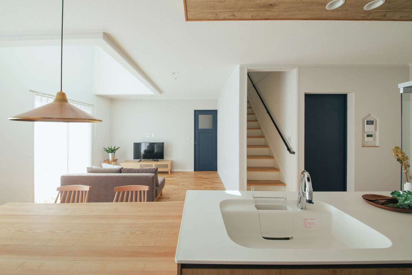 ほっと住まいる【自然素材、間取り、インテリア】キッチンからLDK全体が見渡せる。写真左のドアは玄関へ、階段右側のドアは水回りへとつながる