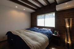 寝室は一面に張られた無垢と現しの梁で、落ち着きをプラス。右手のウォークインは使い勝手まで配慮されている