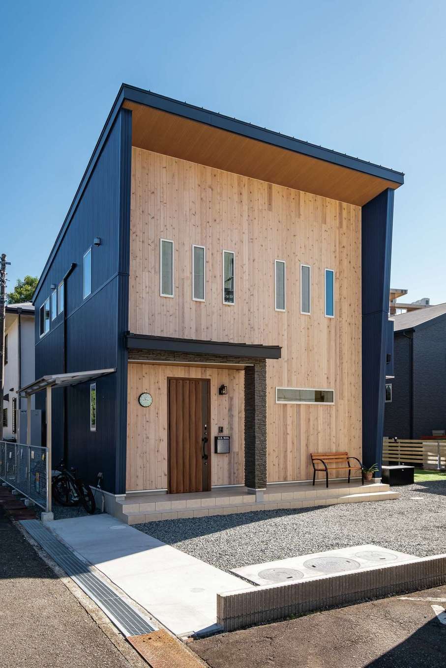 ぽっくハウス【リプルス】【1000万円台、デザイン住宅、子育て】奥さまは全面に無垢が張られたこの外観にときめいた。ネイビーのガルバと組み合わせ、インパクトはありつつも、住宅街にもなじむ表情。窓の形状と配置も外観の印象にひと役買っている。通り側にはアメリカンフェンスを設置