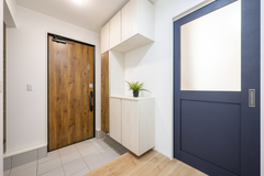 玄関にはベビーカーやアウトドア用品の片付けに便利な土間収納を設計。ネイビーの建具もお洒落。玄関ドアは最高峰の断熱ドアであるYKKAPWのイノベストを使用。