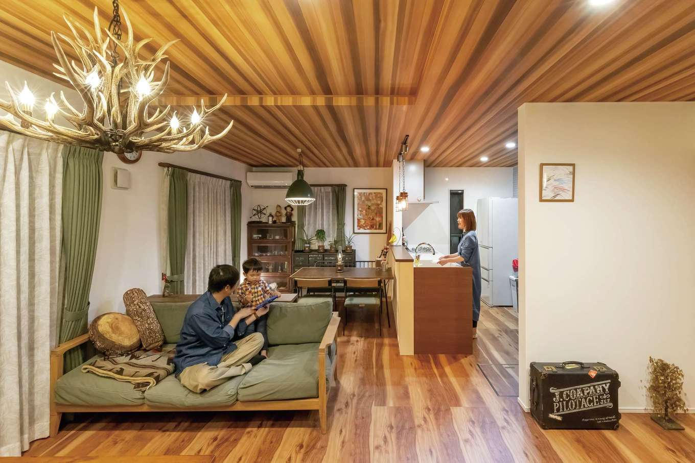 JUST LUCKY HOUSE（山田工務店）【デザイン住宅、ガレージ、インテリア】約20畳のLDK。床と天井に木目調のクロスを貼ってぬくもり感を演出した。ご主人が北海道の職人にオーダー制作してもらった「鹿角のシャンデリア」が家族の成長をあたたかく見守っている