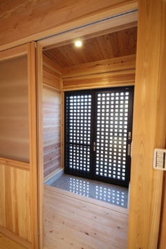 木材をふんだんに使った温かみのある玄関。格子戸から光が差し込み、開放感を感じる設計。