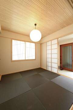 玄関土間に隣接した和室。スギ板に細かい筋を入れた天井、黒い畳、手の込んだ創作の障子戸を用いたこだわりの空間