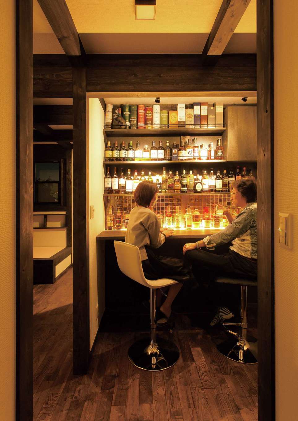 サイエンスホーム【1000万円台、趣味、自然素材】2階フリースペースの一角に設けたショップ仕様のバーカウンター。ウイスキーが映えるよう壁面はブラックに、カウンターの間接照明で上質感を演出。夫婦でしっぽり宅呑みしたり、友人を招いて大好きなウイスキーを楽しみたいという夢が実現した