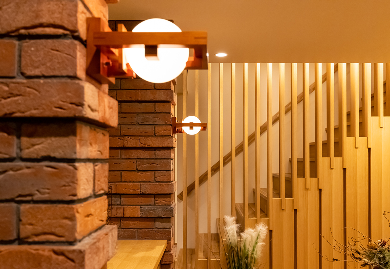 住宅工房 アリアンス【富士市伝法2001-35・モデルハウス】木とガラスで構成されたブラケットライト「ロビー 1」がレンガをやさしく照らす。ライトの初期の建築様式であるプレイリースタイル（草原様式）を代表する住宅、フレデリック・ロビー邸のリビングルームのためにデザインされた照明器具