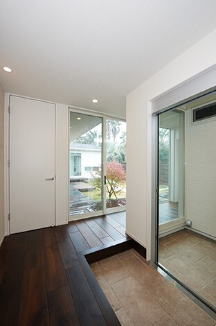 ガラスを通して中庭を臨むことができる玄関ホール。路地のようなアプローチとの対比がゲストに鮮烈なインパクトを与えるドラマチックな演出