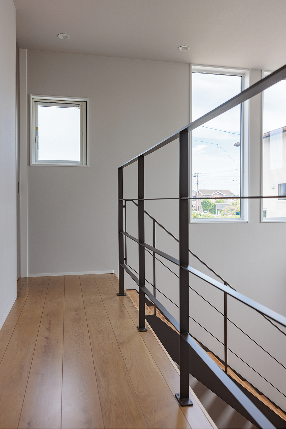 tact design firm【デザイン住宅、子育て、間取り】明るい自然光が差し込む2階の廊下。手摺りにはシンプルなデザインのアイアンを採用し、スタイリッシュな印象を与える