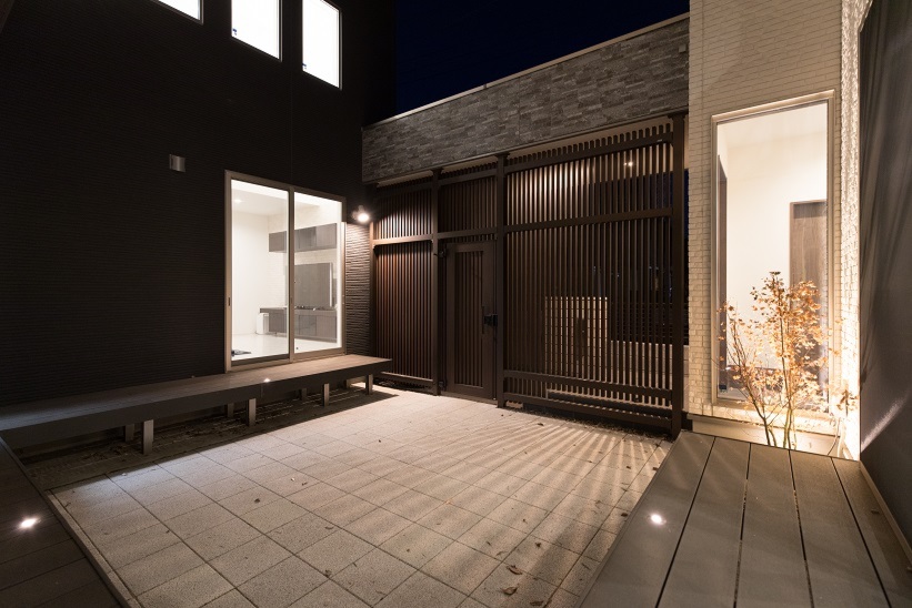 パナソニックビルダーズグループ　エステート住宅産業｜お互いのリビングから見える中庭は住まいの中央に配置。壁に描き出された陰影は、ライトアップされた紅葉によるもの