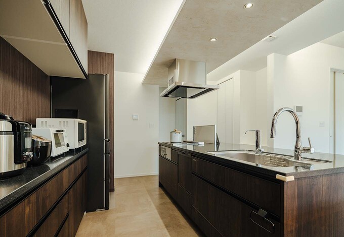 アイランドキッチンをメインにした住まいがNさんの一番の要望。キッチン上の天井を下げて間接照明を配し、空間の広がりを演出