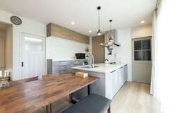 キッチンとダイニングテーブルを一列に並べ、配膳や片付けの効率がアップ。キッチン背後の白いドアの奥に水回りを配置し、家事動線もショートカットした