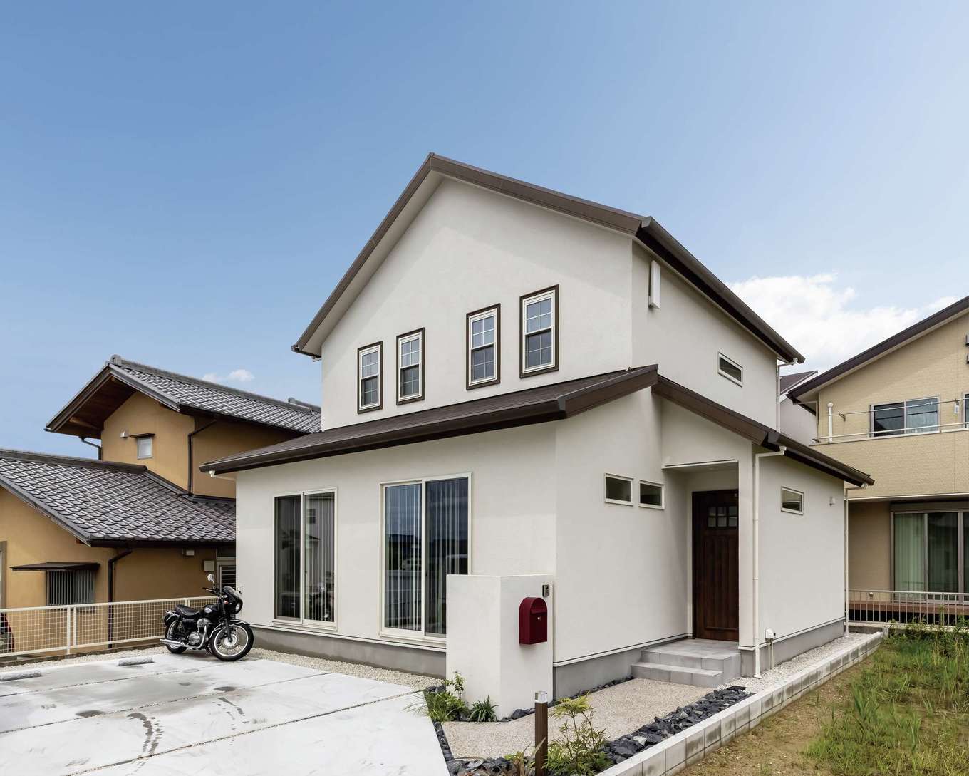 SEVEN HOUSE/セブンハウス【子育て、収納力、間取り】三角屋根と白い塗り壁の外観。4連のブラウンの窓枠がおしゃれ。広い駐車スペースでBBQを楽しむ予定も