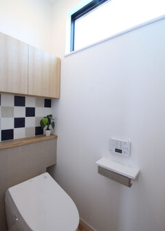 トイレには収納＆飾り棚を造作。ベージュとブルーを組み合わせたタイルコーディネートは、1階の洗面とおそろいのデザイン