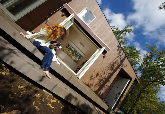 外観。森と一体となるようにグッドデザイン賞を受賞した木目調サイディングを外壁に採用。開閉できるオーニングテントや愛犬用の温水式シャワー水栓も外部に設置。ウッドデッキを階段状に設計することで住宅全体の立体感を作り出した